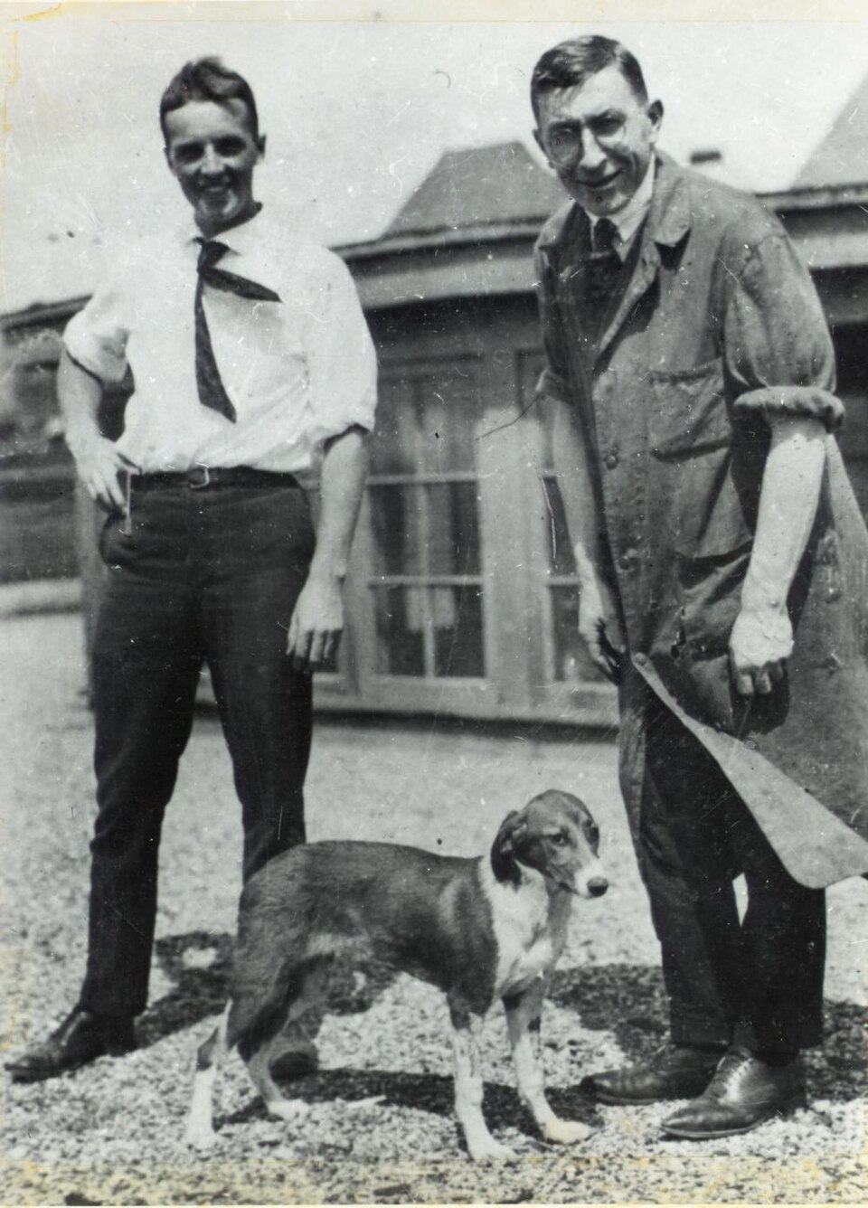 Frederick Banting and Charles Best standing with a dog on a rooftop in Toronto.