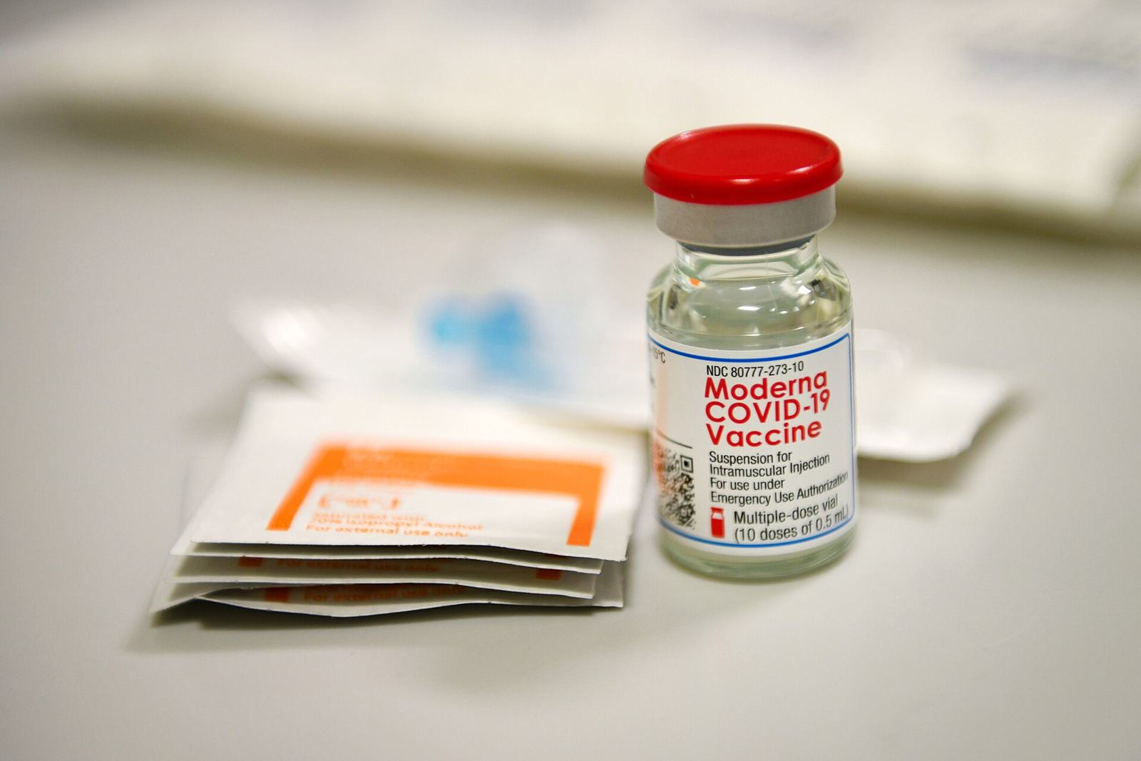 A vial of Moderna COVID-19 vaccine on a table.